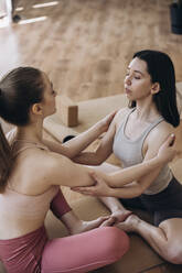 Junge Frauen üben gemeinsam Entspannungsübungen im Yogastudio - KANF00017