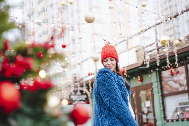 Smiling woman wearing blue coat standing in city - NLAF00094