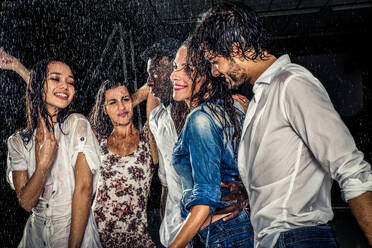 Eine Gruppe von Freunden tanzt im Regen - Multiethnische Menschen feiern eine Party - DMDF04218