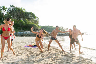 Group of happy friends on a tropical island having fun - Young adults playing together on the beach, summer vacation on a beautiful beach - DMDF04231