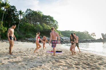 Group of happy friends on a tropical island having fun - Young adults playing together on the beach, summer vacation on a beautiful beach - DMDF04233