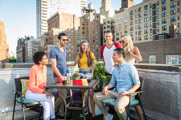 Junge, glückliche Menschen bei einem Grillabend auf einem Dach in New York - Eine Gruppe von Freunden feiert eine Party und hat Spaß - DMDF04261