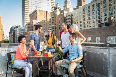 Junge, glückliche Menschen bei einem Grillabend auf einem Dach in New York - Eine Gruppe von Freunden feiert eine Party und hat Spaß - DMDF04262