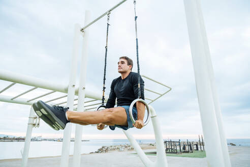 Sportive and athletic man doing functional training exercise at the outdoor gym - Adult athlete doing workout at sunrise at calisthenics park on the beach - Fitness, healthy lifestyle and sport concepts - DMDF04289