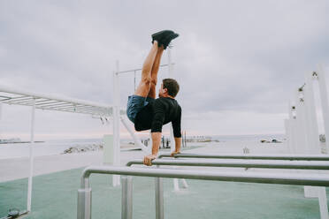 Sportive and athletic man doing functional training exercise at the outdoor gym - Adult athlete doing workout at sunrise at calisthenics park on the beach - Fitness, healthy lifestyle and sport concepts - DMDF04291