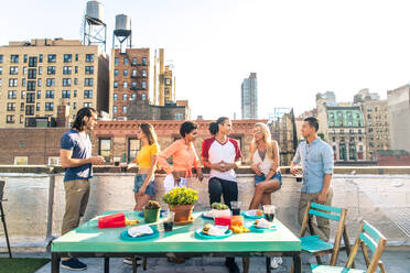 Junge, glückliche Menschen bei einem Grillabend auf einem Dach in New York - Eine Gruppe von Freunden feiert eine Party und hat Spaß - DMDF04307