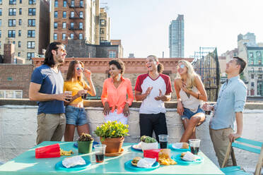 Junge, glückliche Menschen bei einem Grillabend auf einem Dach in New York - Eine Gruppe von Freunden feiert eine Party und hat Spaß - DMDF04309