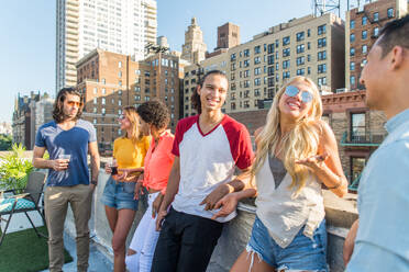 Junge, glückliche Menschen bei einem Grillabend auf einem Dach in New York - Eine Gruppe von Freunden feiert eine Party und hat Spaß - DMDF04312