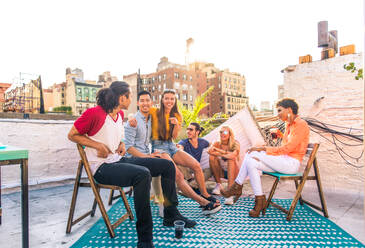 Young happy people having a barbecue dinner on a rooftop in New York - Group of friends having party and having fun - DMDF04321