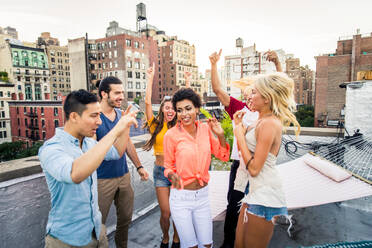 Young happy people having a barbecue dinner on a rooftop in New York - Group of friends having party and having fun - DMDF04324