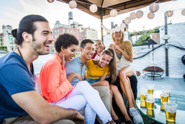 Junge, glückliche Menschen bei einem Grillabend auf einem Dach in New York - Eine Gruppe von Freunden feiert eine Party und hat Spaß - DMDF04336