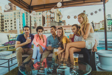 Junge, glückliche Menschen bei einem Grillabend auf einem Dach in New York - Eine Gruppe von Freunden feiert eine Party und hat Spaß - DMDF04338