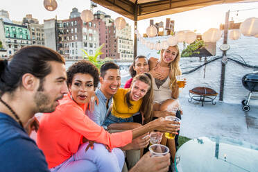 Junge, glückliche Menschen bei einem Grillabend auf einem Dach in New York - Eine Gruppe von Freunden feiert eine Party und hat Spaß - DMDF04342