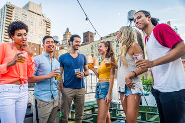 Young happy people having a barbecue dinner on a rooftop in New York - Group of friends having party and having fun - DMDF04345