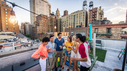 Young happy people having a barbecue dinner on a rooftop in New York - Group of friends having party and having fun - DMDF04347