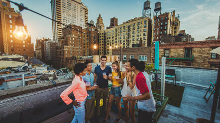 Young happy people having a barbecue dinner on a rooftop in New York - Group of friends having party and having fun - DMDF04348