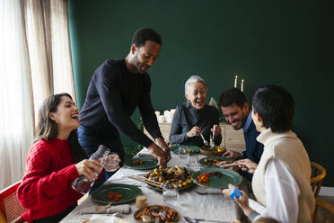 Eine gemischtrassige Familie lacht und genießt das Abendessen zu Hause - EBSF03772