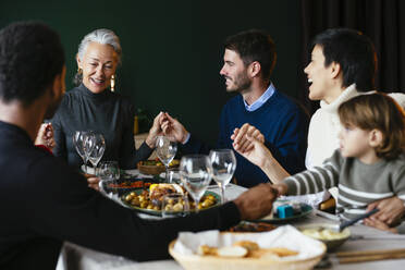 Gemischtrassige Familie beim gemeinsamen Abendessen zu Hause - EBSF03774