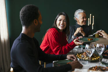 Fröhliche Frau beim Abendessen mit der Familie zu Hause an Weihnachten - EBSF03779