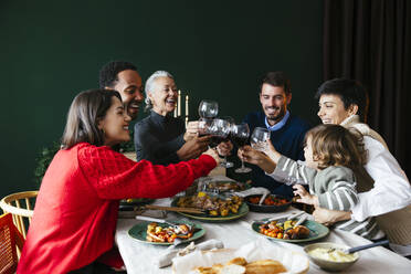 Glückliche Familie stößt mit Weingläsern im Esszimmer zu Hause an - EBSF03797