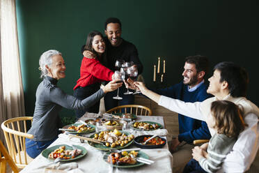 Fröhliche Familie stößt an Weihnachten im Esszimmer mit Weingläsern an - EBSF03803