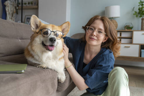 Young woman and Welsh Corgi dog with eyeglasses at home - VPIF08686