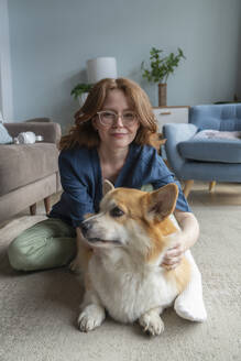 Frau mit Welsh Corgi Hund im Wohnzimmer sitzend - VPIF08688