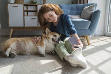 Young woman taking selfie with pet dog on smart phone at home - VPIF08701