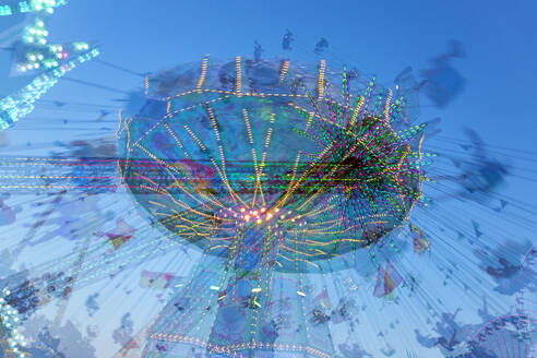 Germany, Bavaria, Wurzburg, Multiple exposure of spinning carousel at dusk - NDF01570