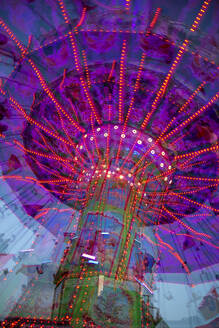 Germany, Bavaria, Wurzburg, Multiple exposure of spinning carousel at dusk - NDF01571