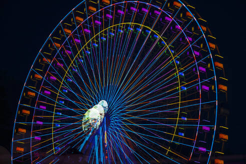 Germany, Bavaria, Wurzburg, Multiple exposure of spinning Ferris wheel at night - NDF01575