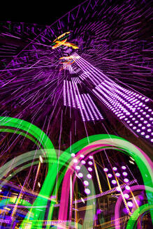 Germany, Bavaria, Wurzburg, Multiple exposure of spinning Ferris wheel at night - NDF01578