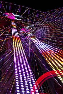 Germany, Bavaria, Wurzburg, Multiple exposure of spinning Ferris wheel at night - NDF01579