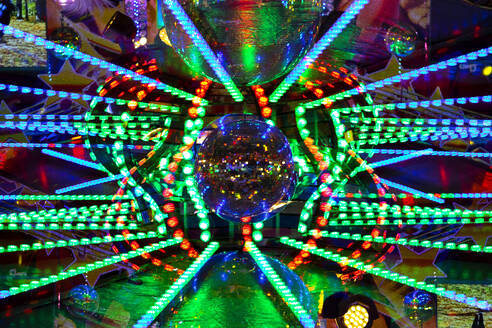 Germany, Bavaria, Wurzburg, Multiple exposure of disco balls and glowing lights in amusement park - NDF01585