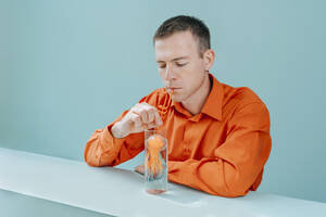 Mann trinkt Wasser mit Quallen im Glas auf dem Tisch - YTF01120