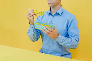 Mann isst Nudeln aus einer Lunchbox im Studio - YTF01125