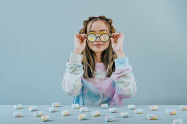Frau mit Kaleidoskopbrille am Tisch mit Marshmallows im Studio - YTF01128