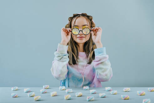 Frau mit Kaleidoskopbrille am Tisch mit Marshmallows im Studio - YTF01128