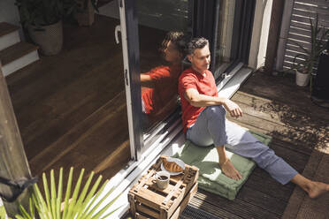 Porträt eines Mannes, der sich auf einem Balkon entspannt - UUF30083