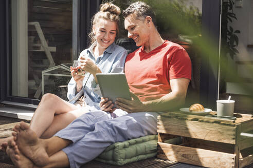 Ehepaar entspannt sich auf dem Balkon mit digitalem Tablet - UUF30095