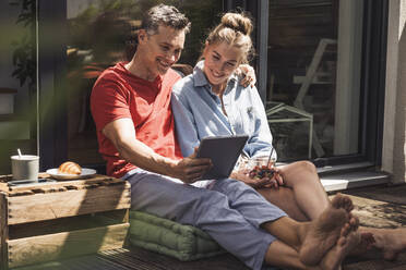 Couple relaxing on balcony with digital tablet - UUF30097