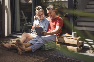 Couple relaxing on balcony with digital tablet - UUF30098