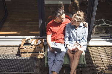 Couple relaxing on balcony with digital tablet - UUF30099