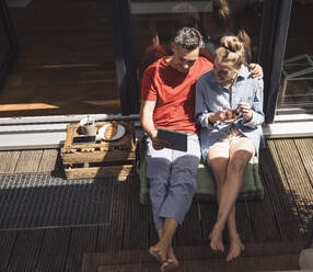 Couple relaxing on balcony with digital tablet - UUF30100