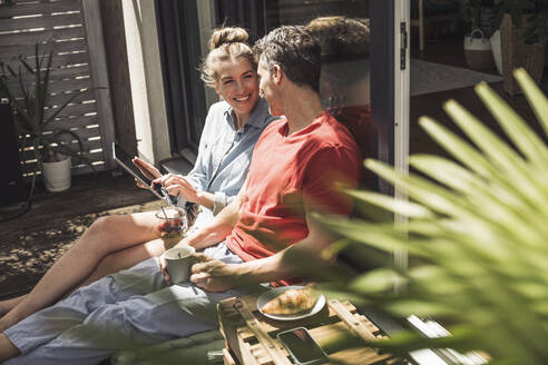 Ehepaar entspannt sich auf dem Balkon mit digitalem Tablet - UUF30101