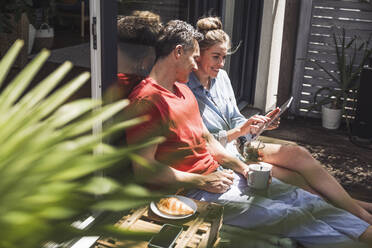 Couple relaxing on balcony with digital tablet - UUF30102