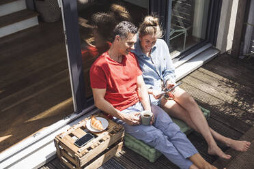 Ehepaar entspannt sich auf dem Balkon mit digitalem Tablet - UUF30103