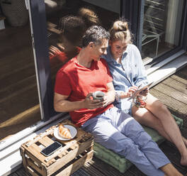 Couple relaxing on balcony with digital tablet - UUF30104