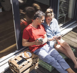 Ehepaar entspannt sich auf dem Balkon mit digitalem Tablet - UUF30104