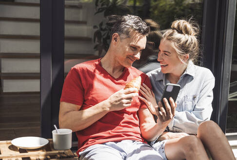 Couple relaxing on balcony with smart phone - UUF30106